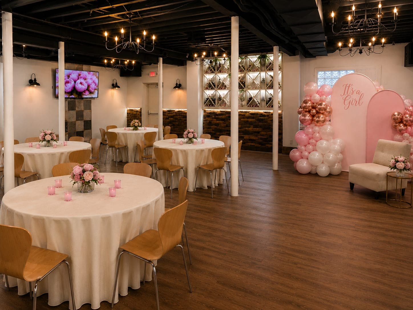 A pink It's a Girl balloon backdrop beside the wine racks at a baby shower in the Wine Cellar at Crown Tavern in Glen Mills, PA