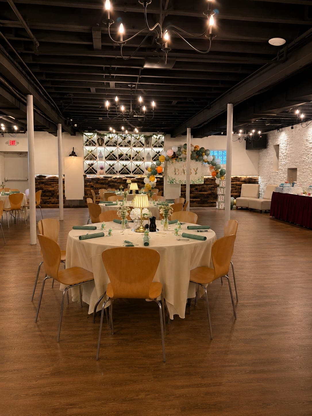 Round tables set for a baby shower under a sage and white balloon arch in the Wine Cellar at Crown Tavern in Glen Mills, PA