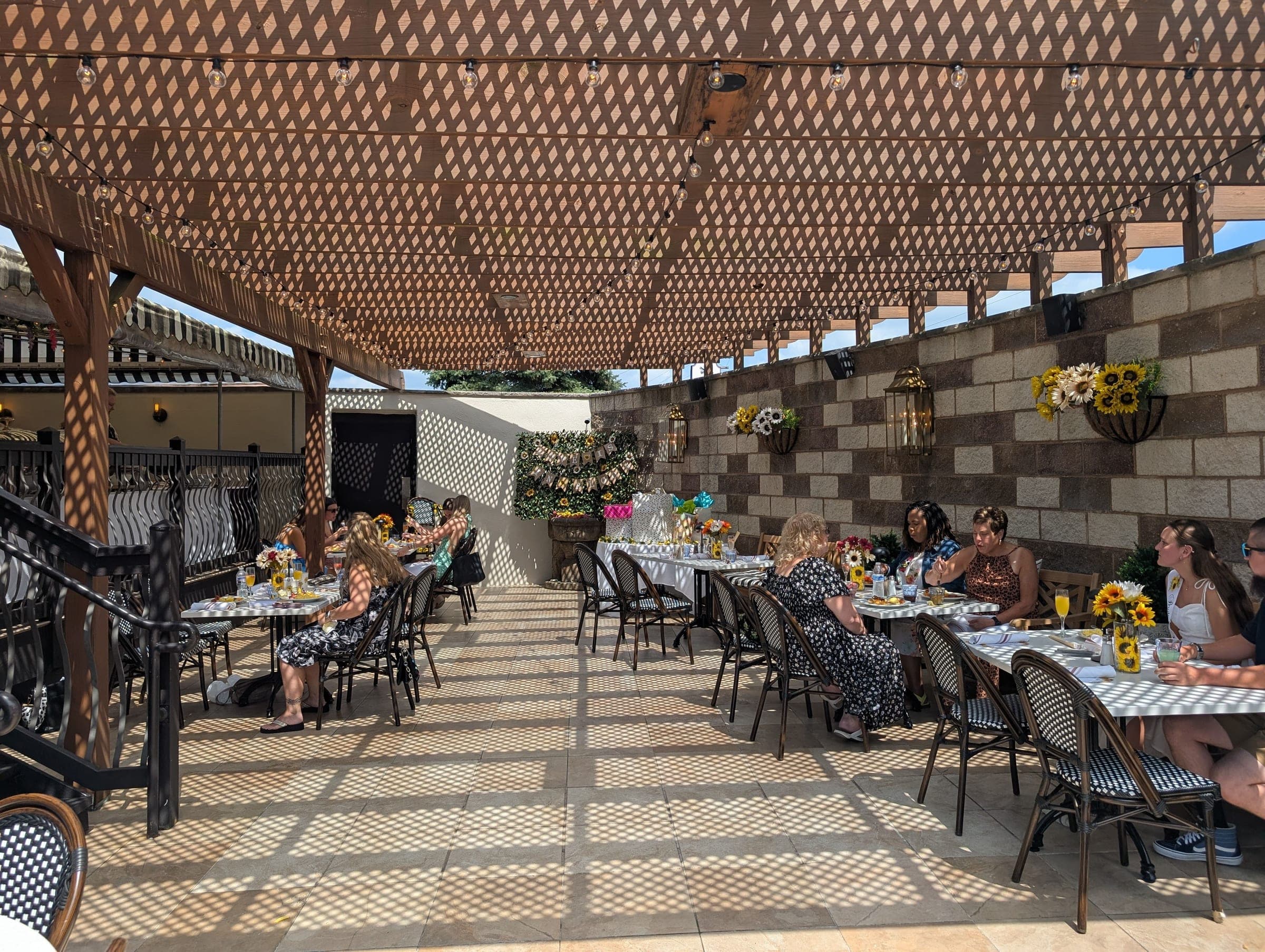 Guests seated for a bridal shower brunch under the pergola on the garden patio at Crown Tavern in Glen Mills, PA