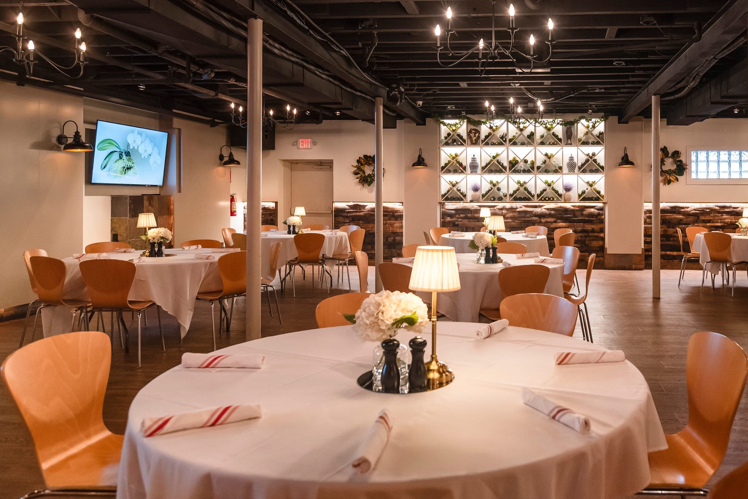 The Wine Cellar private banquet room with round tables and stone walls, set for a large rehearsal dinner at Crown Tavern in Glen Mills, PA